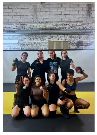 Équipe féminine de MMA souriante après un entraînement, posant en tenue de combat